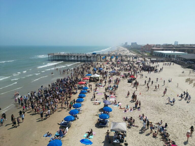 A crowded beach day with people and umbrellas